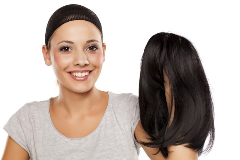 Young Woman With A Wig Cap On Her Head Holding A Wig In Hand